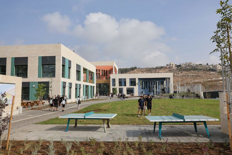 חצר קמפוס בית ספר מודרני בירושלים עם מדשאות ומתקני ספורט